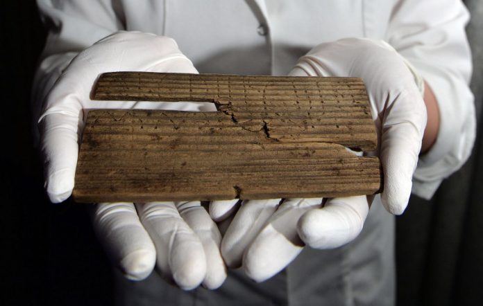 Luisa Duarte, a conservator for the Museum of London, holds a piece of wood with the Roman alphabet
